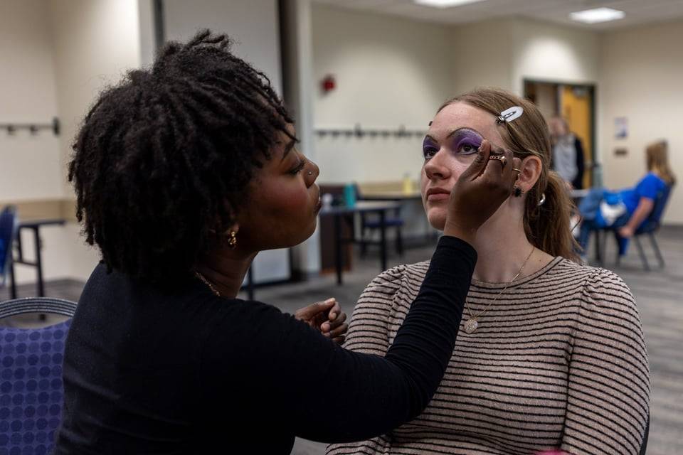 Student giving drag make-up to another student
